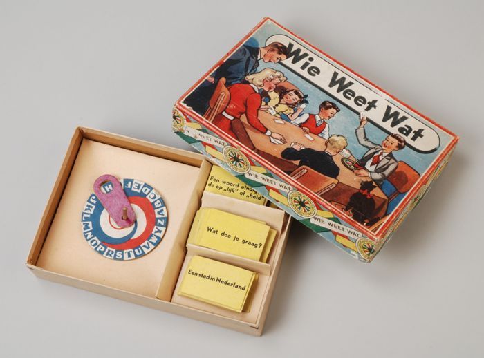 Collectiestuk: Spel "Wie Weet Wat" doos: gele kaartjes, draaischijf met letters en paarse wijzer aan stokje | Museum